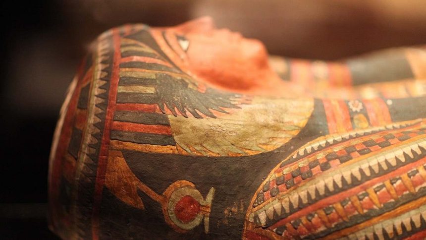 Close-up of an ancient Egyptian mummy's face, showing intricate painted designs and details.